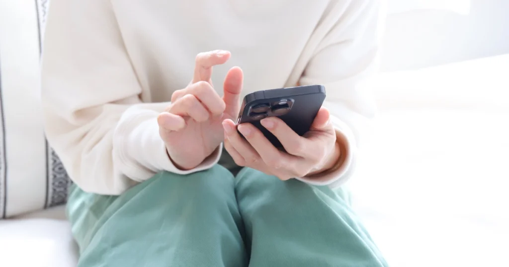 相談者がスマートフォンを手に取り、慎重に電話をかけようとしている様子